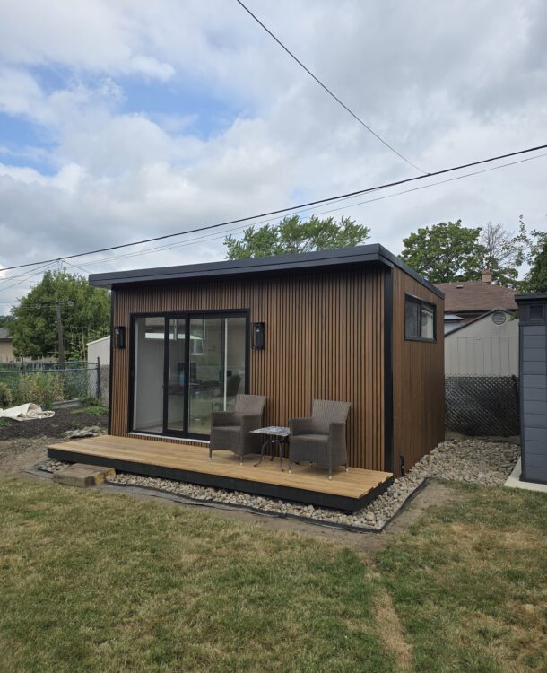 Modern custom-built garden room by Garden Haus, surrounded by lush landscaping, stone pathways, and outdoor seating area.