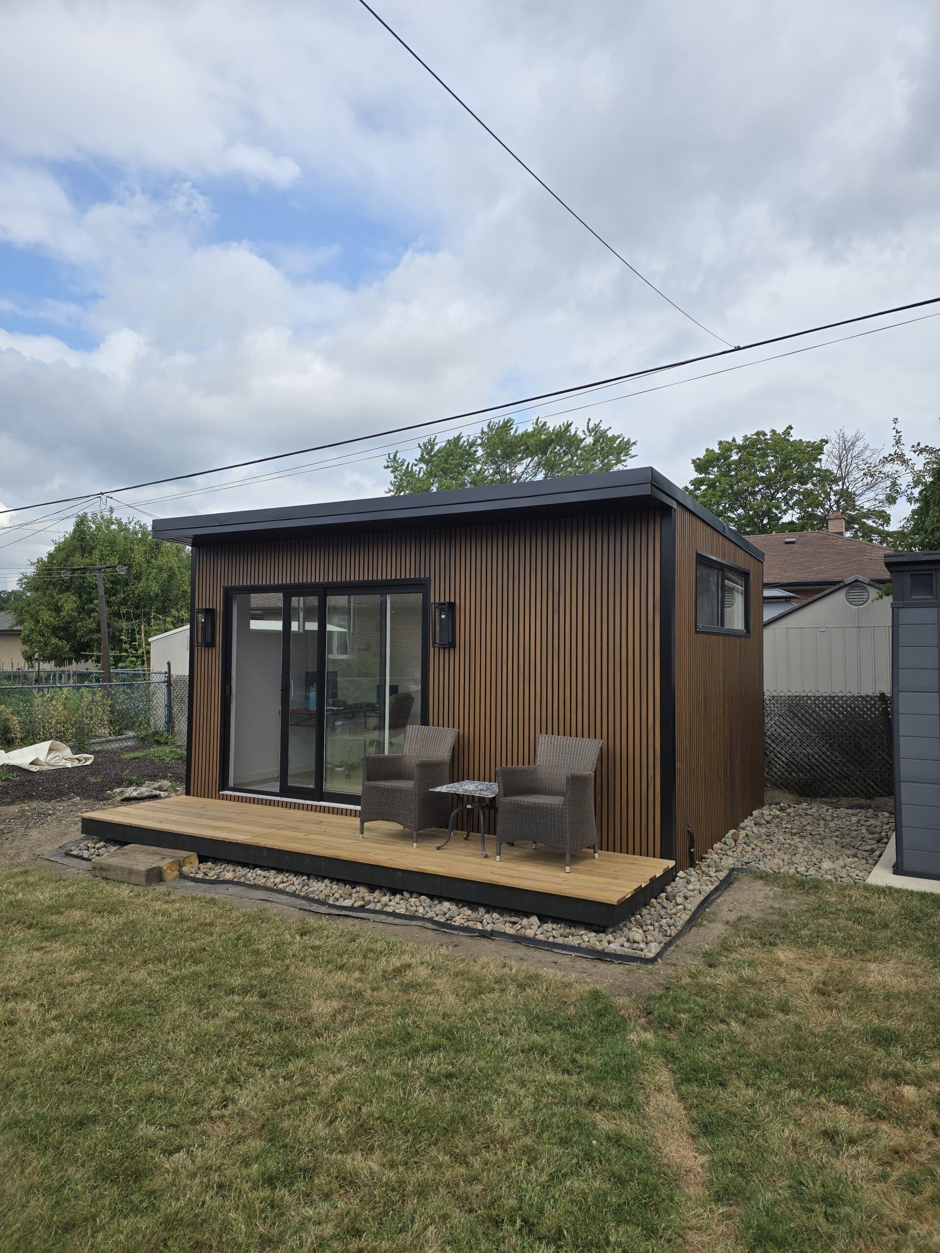 Modern custom-built garden room by Garden Haus, surrounded by lush landscaping, stone pathways, and outdoor seating area.