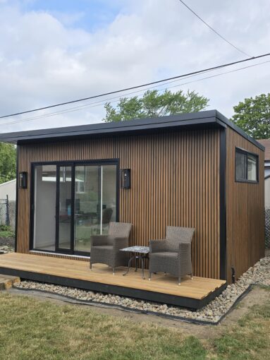 Modern custom-built garden room by Garden Haus, surrounded by lush landscaping, stone pathways, and outdoor seating area.