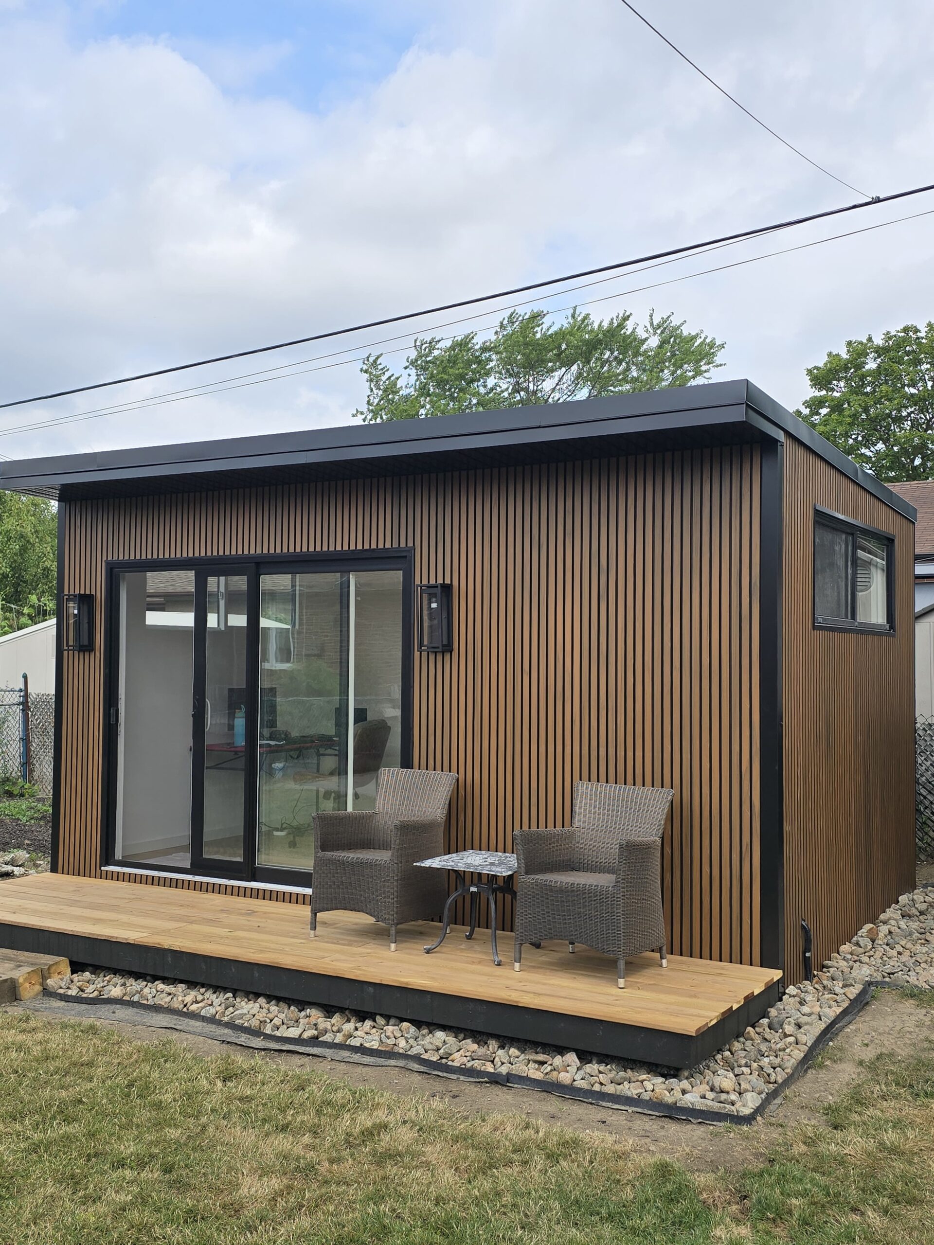 Modern custom-built garden room by Garden Haus, surrounded by lush landscaping, stone pathways, and outdoor seating area.